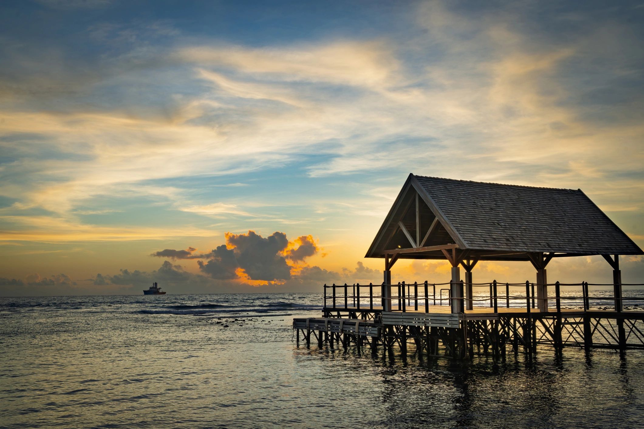 Sunset over calm ocean with pier